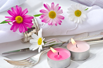 Obraz na płótnie Canvas Romantisches Gedeck mit Kerzen und Gänseblümchen