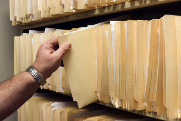 Human Hand Pulls File Folder off Shelf of Client Files