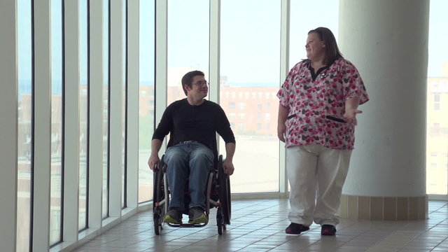 Man in wheelchair talking with nurse in hospital