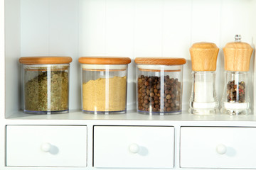 Beautiful white shelves with spices in glass bottles