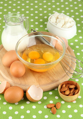 Broken egg in bowl and various ingredients next to them