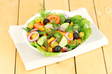 Fresh salad in plate on wooden table
