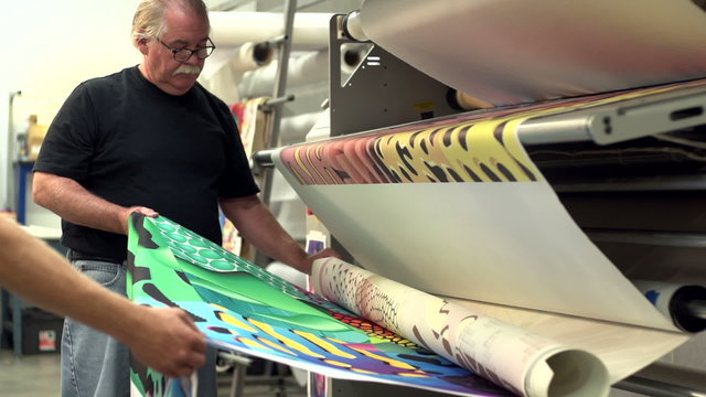 Printers pulling a finished textile out of a printer