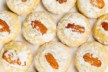 Cookies with almond nuts and sugar powder on plate, top view