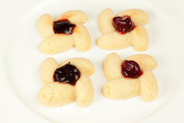 Four cookies with preserved cherry in center on plate