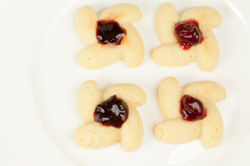 Four cookies shaped as flower with preserved cherry in center