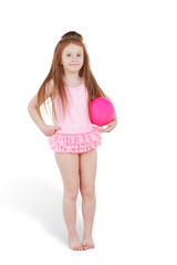 Fototapeta na wymiar Mała rudowłosa dziewczyna w różowym stroju kąpielowym z piłką pod pachą