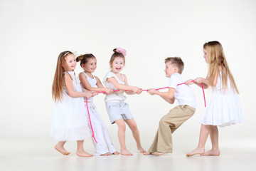 Five happy little children in white clothes draw over pink rope.