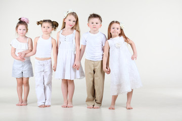 Fototapeta premium Four cute little girls and one boy in white clothes stands