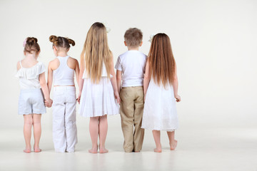 Naklejka premium Back of four cute little girls and one boy in white clothes