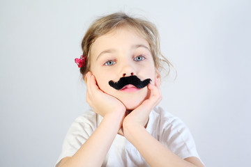 Little melancholy girl in white with glued fake black mustache.