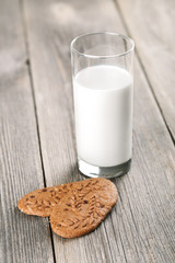 Glass of milk with whole grain cookies on wooden table.