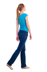 back view of walking  woman  in   jeans and shirt.