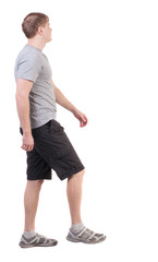 Fototapeta premium Back view of walking handsome man in shorts and sneakers