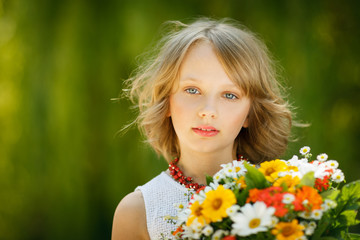 Girl with bunch of flowers standing outdoors