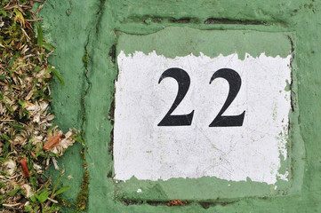 white tile with the number 22 on a green background painted ceme
