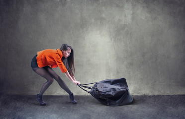 Beautiful woman carrying heavy bag  with some difficulty