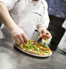 Closeup hand of chef baker in white uniform making pizza at kitc