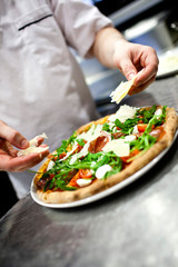 Closeup hand of chef baker in white uniform making pizza at kitc