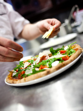 Closeup hand of chef baker in white uniform making pizza at kitc