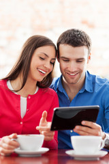 Couple using digital tablet in cafe