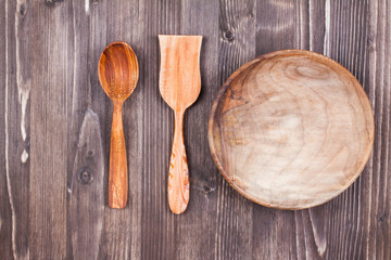 Wooden spoon, plate, spatula on wood texture background