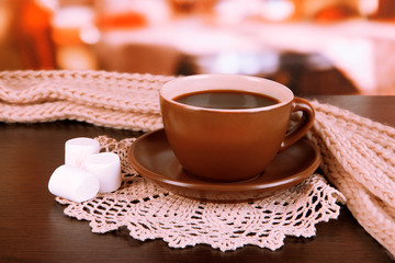 cup of coffee with scarf on table in room