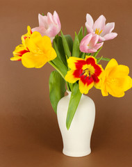 Beautiful tulips in bucket on brown background