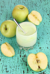 Delicious yogurt in glass with apple on wooden table close-up