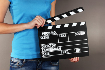 Movie production clapper board in hands on grey background