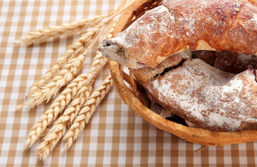 Taste croissants in basket on tablecloth.