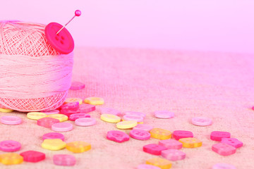 Beautiful buttons and a ball of yarn on a pink background