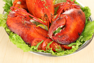 Red lobster on platter with vegetables on wooden table close-up