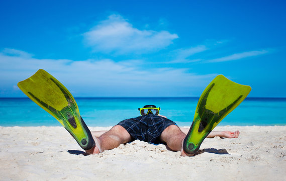 Tourist with flippers laying on sand beach
