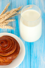 Bread roll and glass of milk on blue wooden background