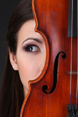 Beautiful young girl with violin on grey background
