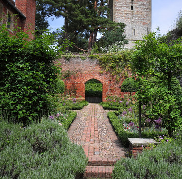 Garden path leading to a red brich arch