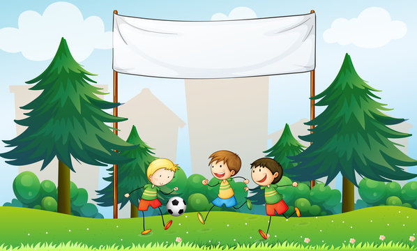 Three boys playing soccer below an empty banner