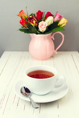 Fototapeta na wymiar Cup of tea on wooden table with rose flowers