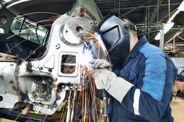 repairman welding metal body car