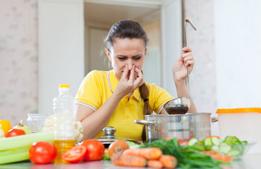 woman holding her nose because of bad smell from soup