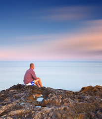 Man sitting on a rock by the sea