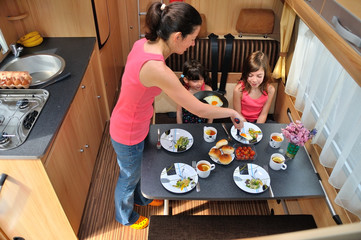 Family eating together in RV interior, travel in camper