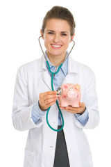 Medical doctor woman listening piggy bank with stethoscope