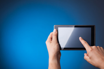 Hands holding Tablet PC on blue