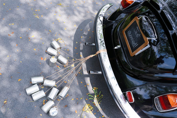 Rear view of a vintage car with just married sign and cans attac