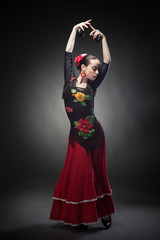 young woman dancing flamenco with castanets on black - obrazy, fototapety, plakaty