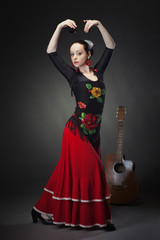young woman dancing flamenco with castanets on black