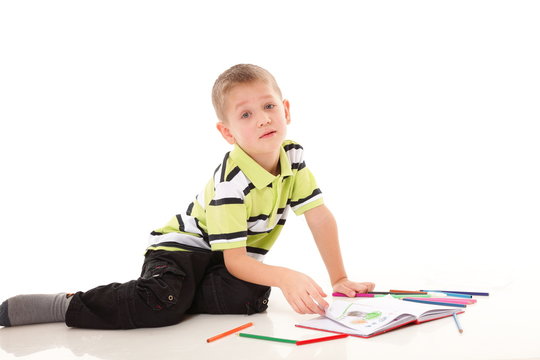 Young boy draws with color pencils isolated