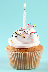 tasty birthday cupcake with candle, on blue background